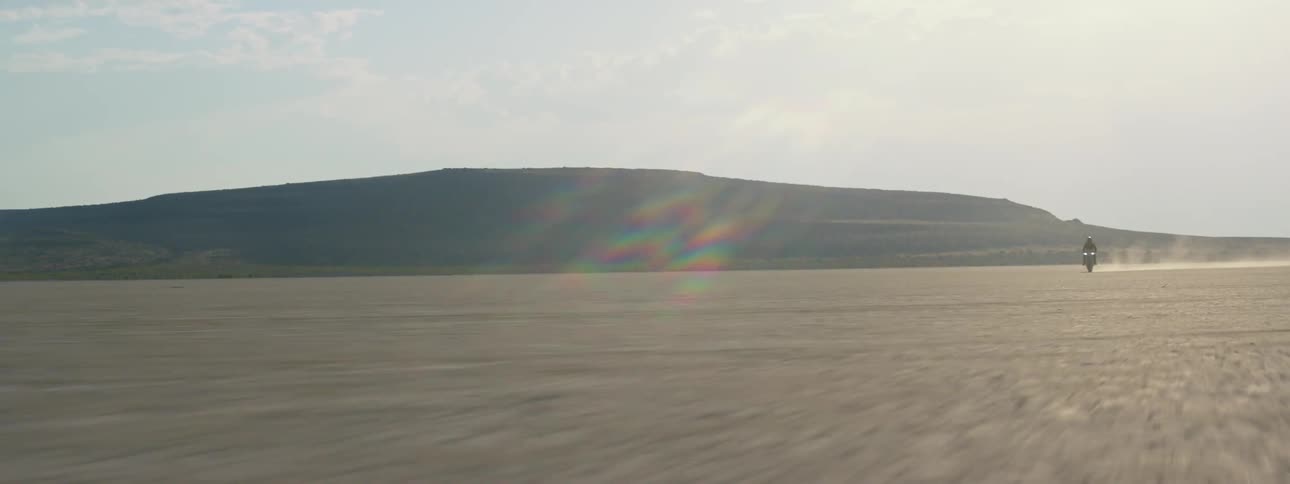 A person rides in the desert on a motorcycle