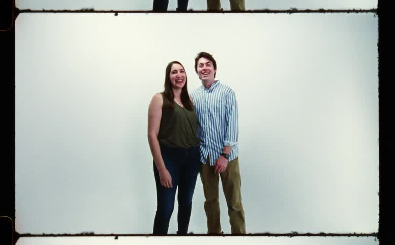 Man and woman laughing and touching each other poses for the camera in front of white screen backdrop in photography studio
