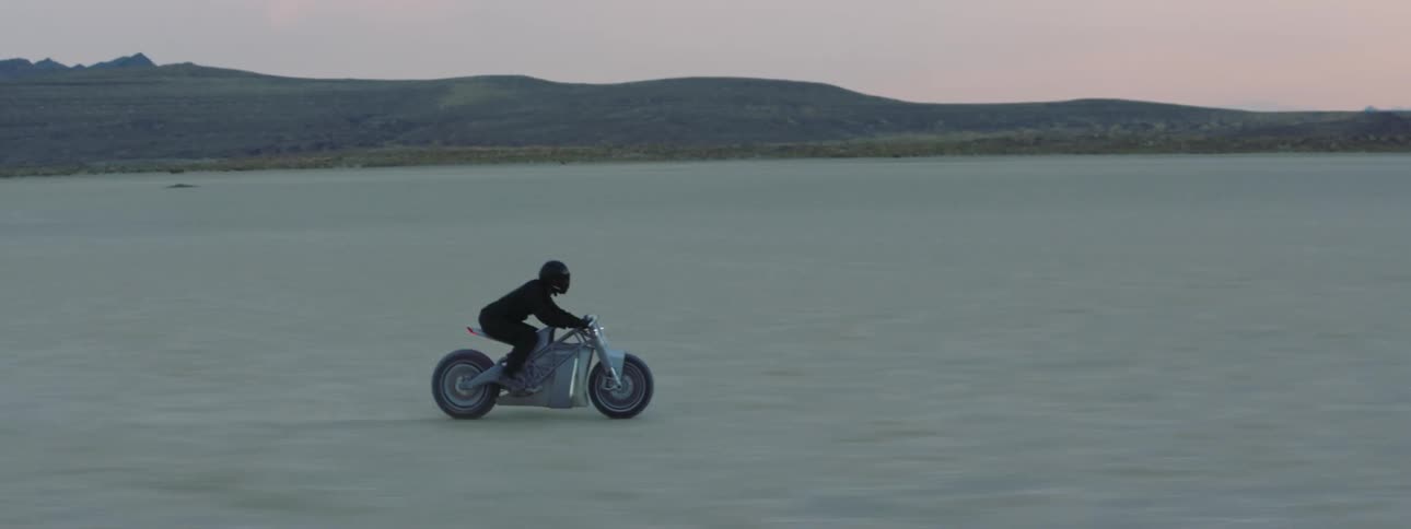 A person driving a motorcycle through the wide open landscape