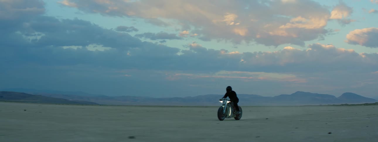 A person is riding their motorcycle while the sun is setting