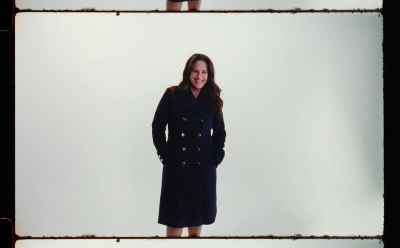 A woman is smiling while wearing a coat