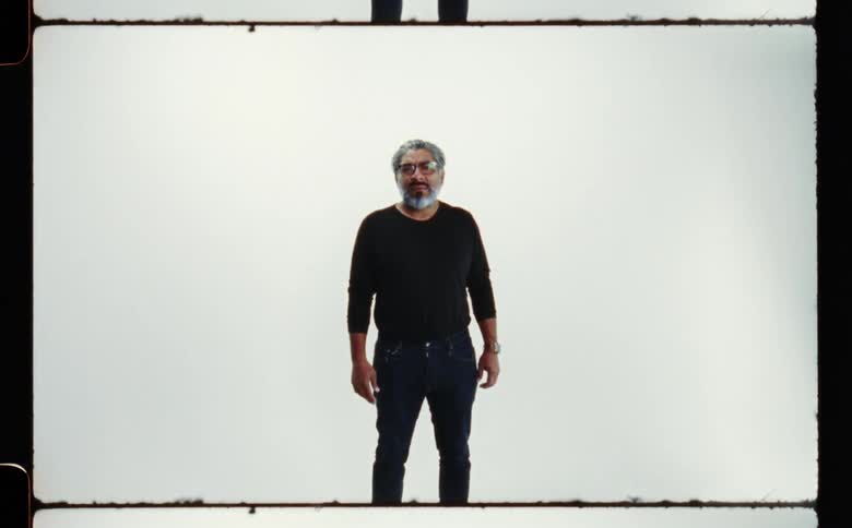 A man is posing for the camera and wearing glasses