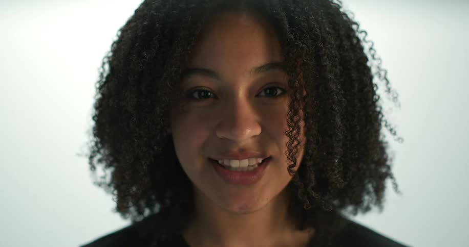 Young woman smiling at camera and laughing looks off camera and says hi