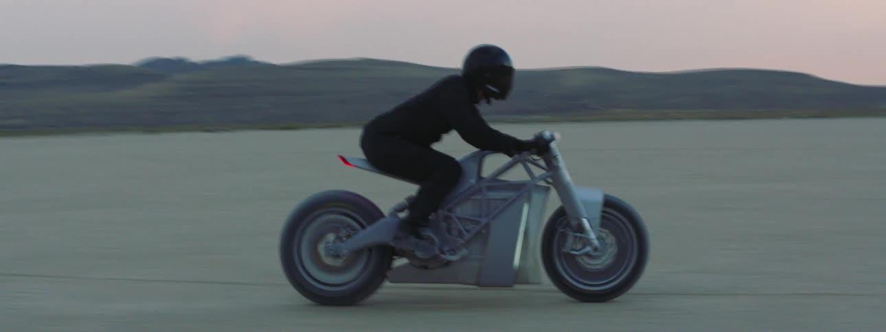 A person is driving a motorcycle through desert sand