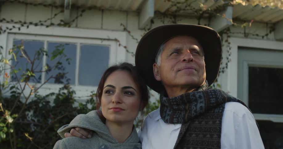 A man and his daughter embrace while standing outside their home