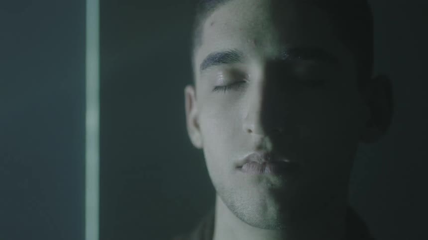 A man's eyes are closed as lights flash on him