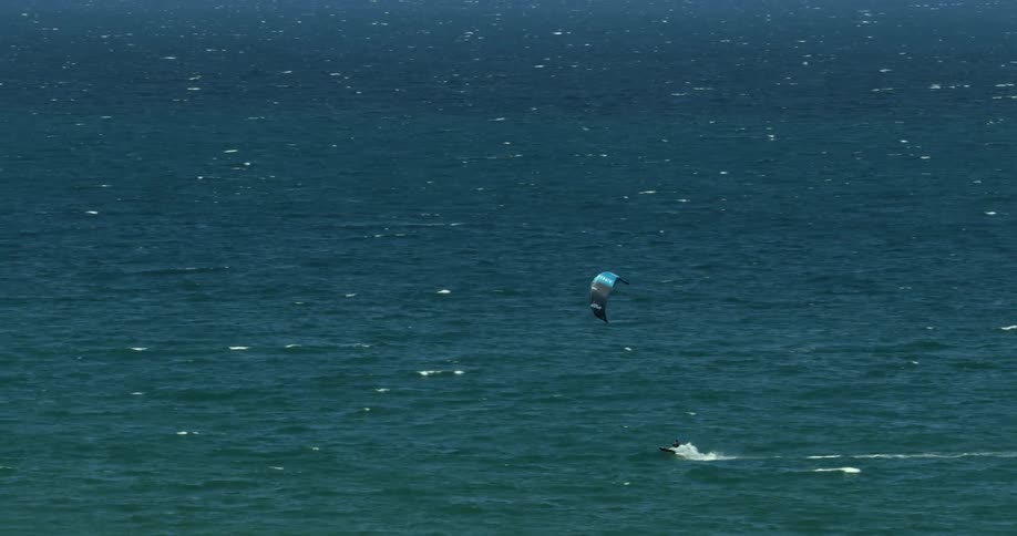 A person is kitesurfing in the water with a kite