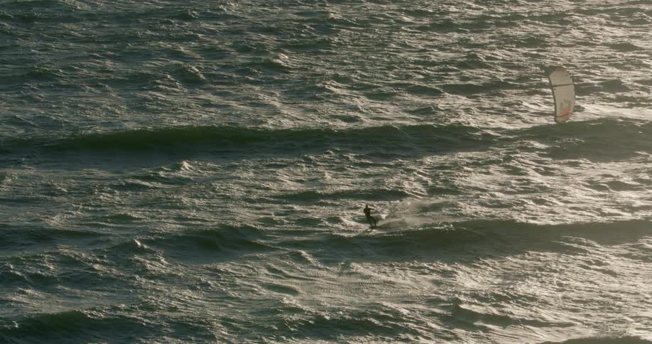 A person kite surfs in the waves of the open ocean