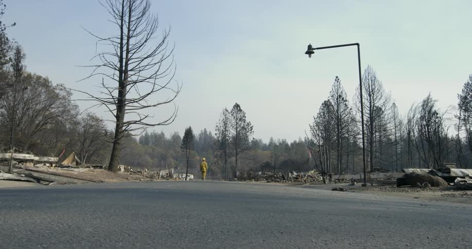 A fireman walks down a street with missing and destroyed houses torn from their foundations