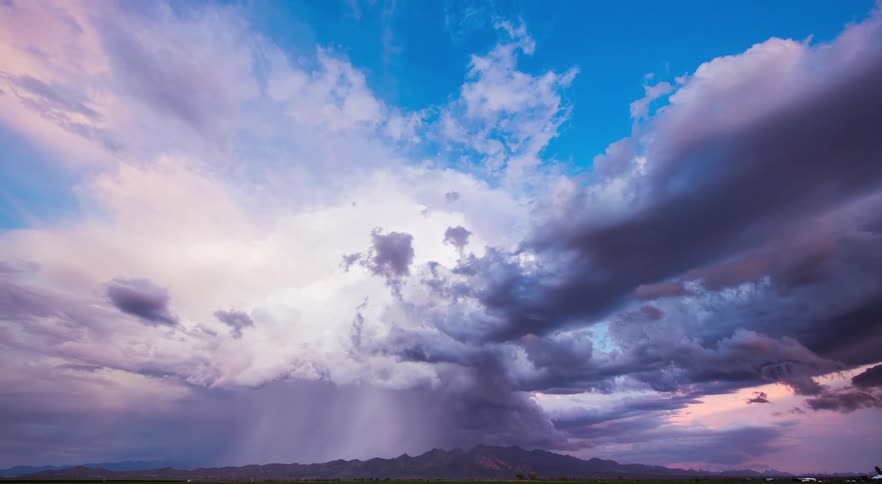 Lightning is striking and rain pouring from storm clouds flowing over mountains