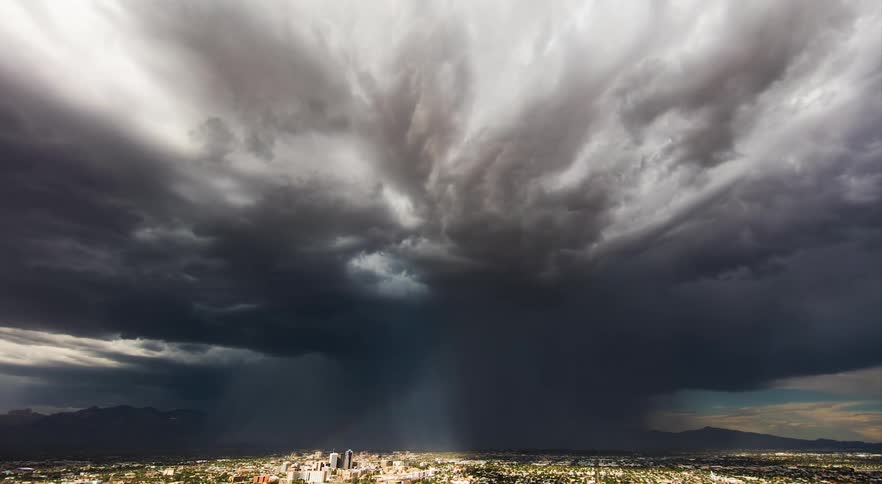 Automobiles travel on the busy streets as dark storm clouds move over town