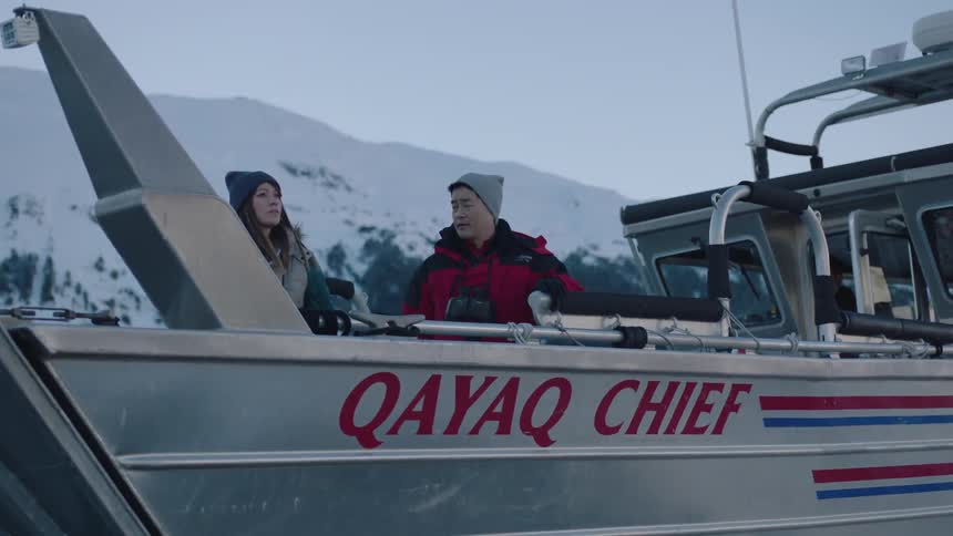 A man and woman on a boat point toward something