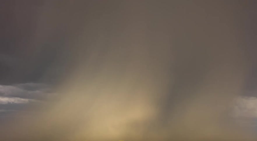 Storm clouds move over rural land as lightning flashes and hits the ground