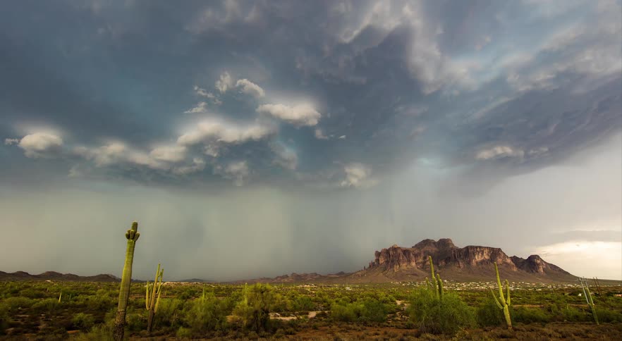 Lightning is striking from storm clouds that are forming and flowing over desert wilderness