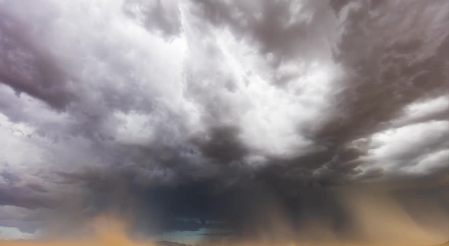 A large storm with lightning forming and rolling across a desert field
