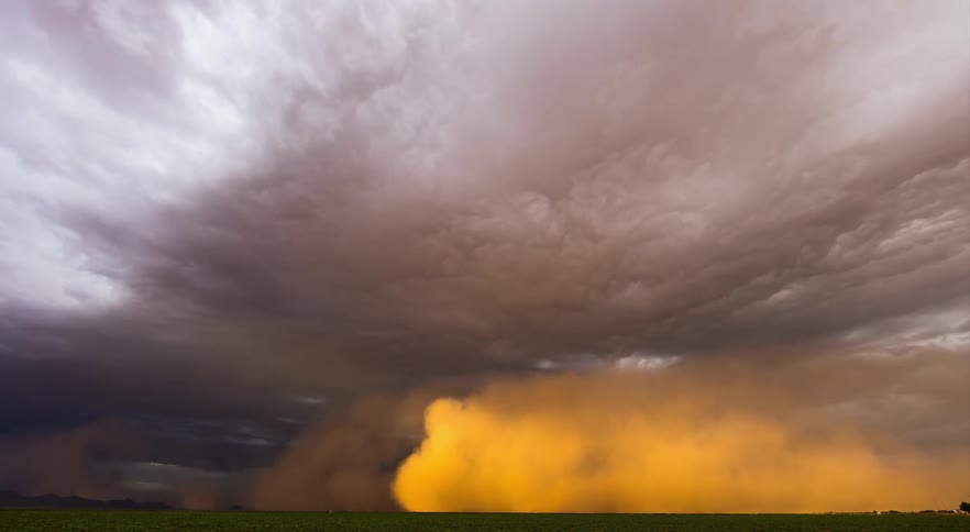 A dust storm forming and rolling across the green field
