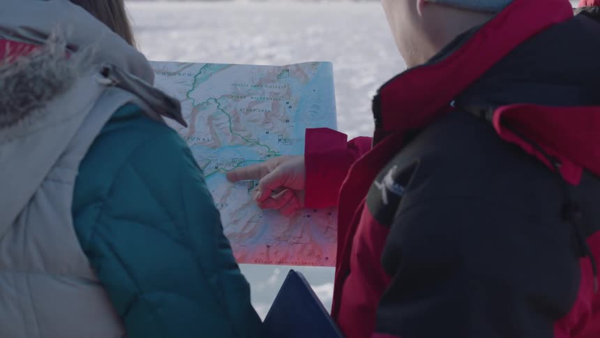 Two people looking at a map outside in the snow