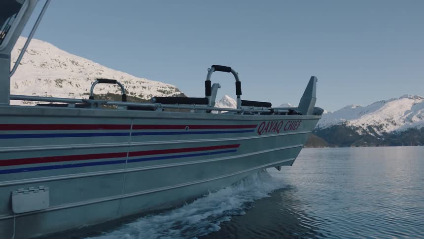A boat travels through a lake near a mountain