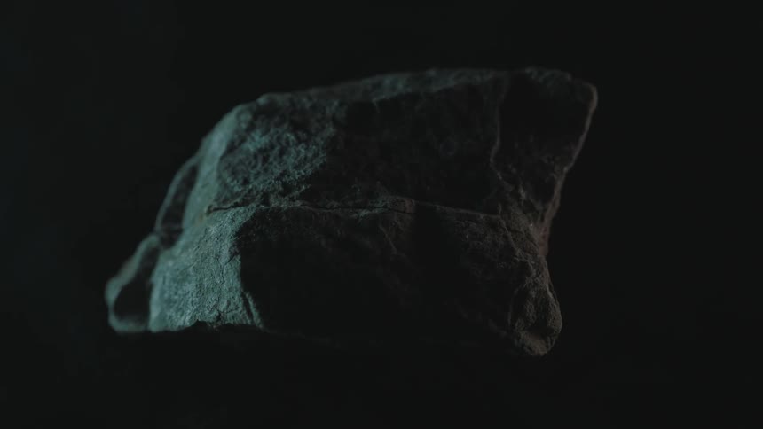 Light reflects on a stone revolving in the dark