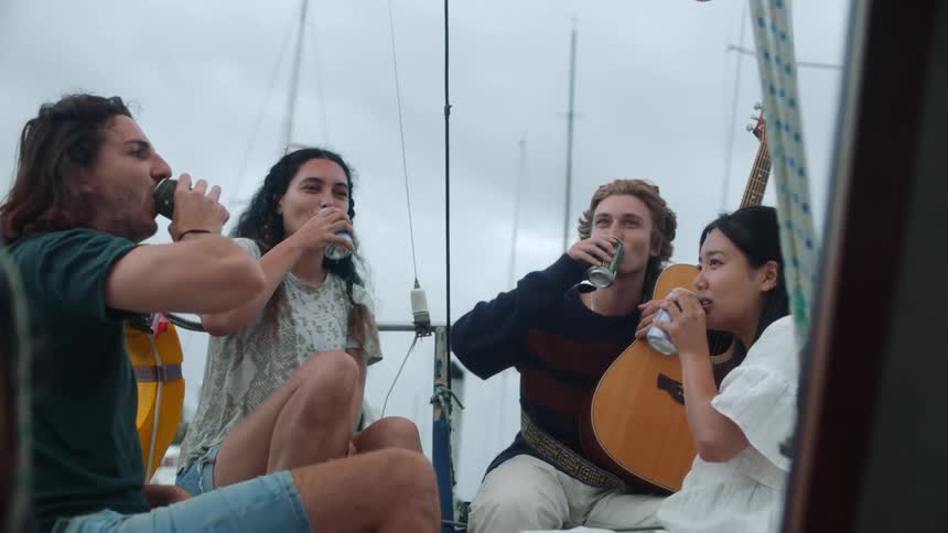 A group of friends toast and drink beer on a boat
