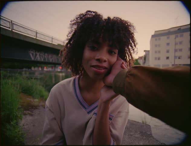 Man touches womans cheek near river with bridge