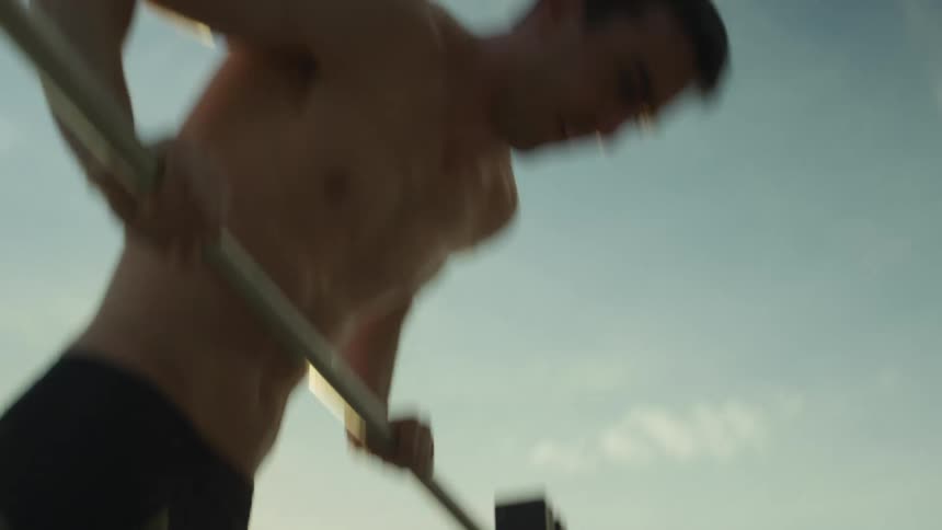 A man does pull ups on fitness equipment at a beach