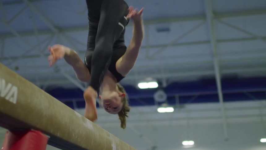 A girl does a front flip in the gym