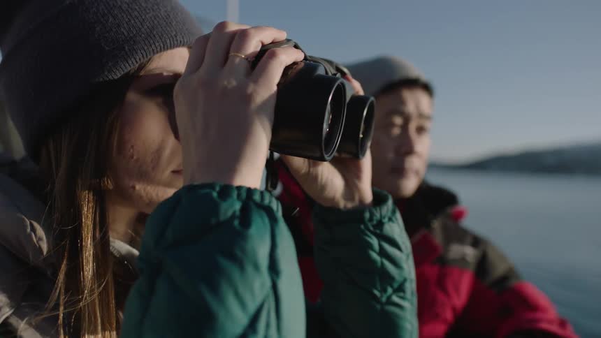 A woman on a boat looks through binoculars