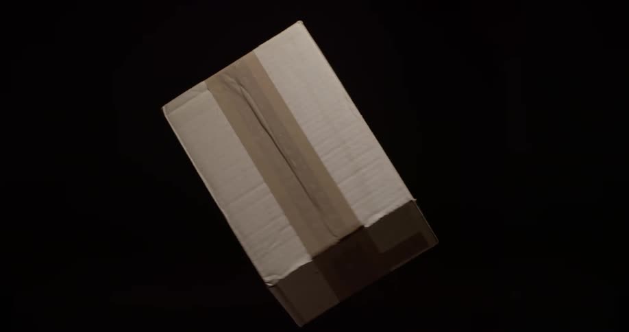 A neutral cardboard shipping box spinning in front of a black background during fast express delivery from an online store