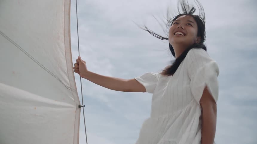 A woman smiling while standing on a sailboat at sea