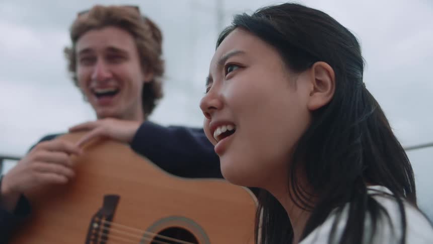 A man and a woman beaming with happiness the man holding a guitar instrument and the two of them clearly enjoying each others company