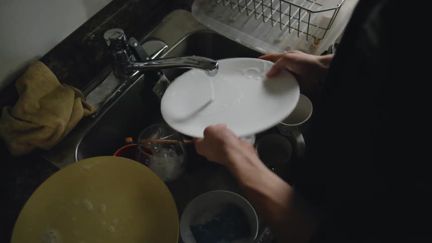 A person washing the dishes in the kitchen