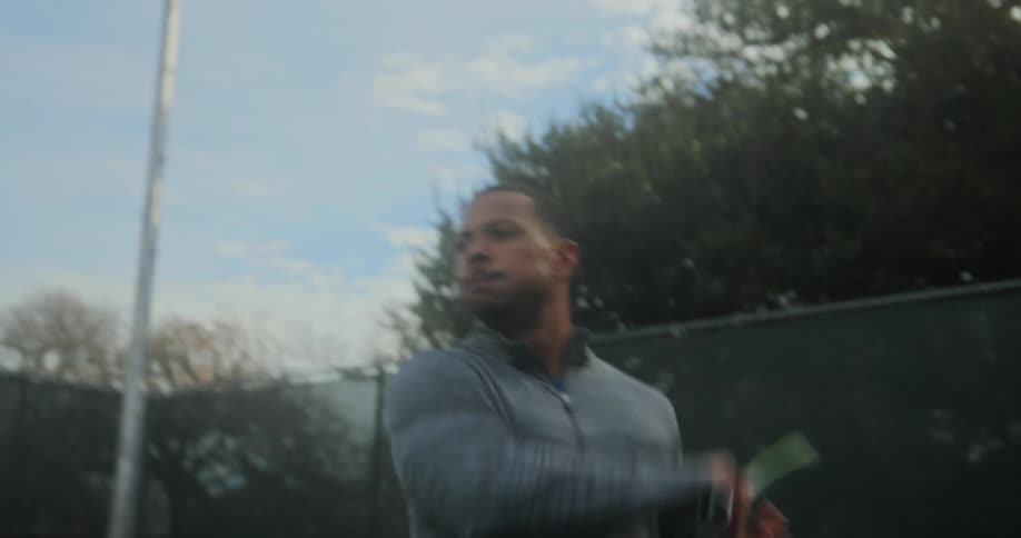 Determined man with gray shirt plays tennis in the court