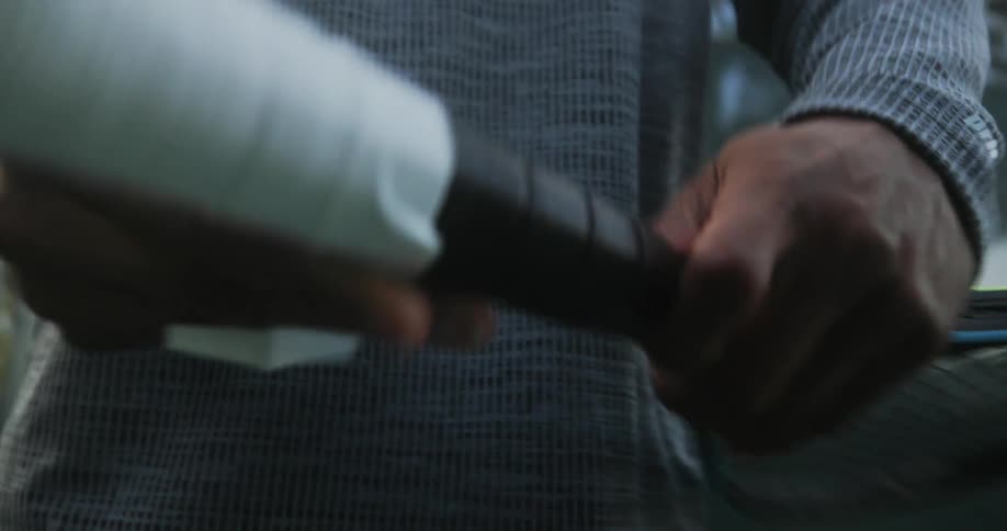 A man is taping the handle of his tennis racket