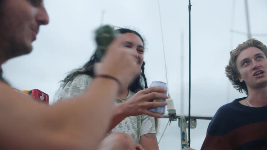 A group of friends hold up their drinks for a toast on a boat