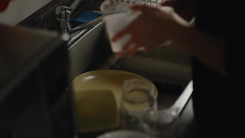 Someone washing dishes in the kitchen with only her hand showing