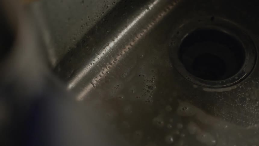 Close up of the hand of a person cleaning and scrubbing the kitchen sink