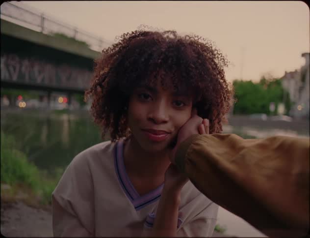A man is touching a females face while sitting outdoors