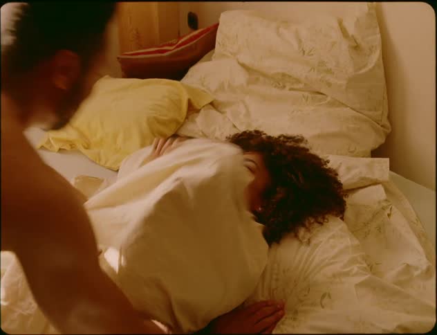 Woman underblanket holds mans face and pushes him away playfully lying in bed in bedroom