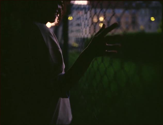 A woman drags her hand along the fence