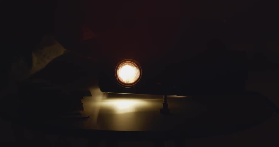 Someone playing with the switch on a desk lamp flipping it on and off in a repetitive motion