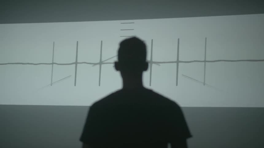 Silhouette of a man standing in front of a screen flashing designs