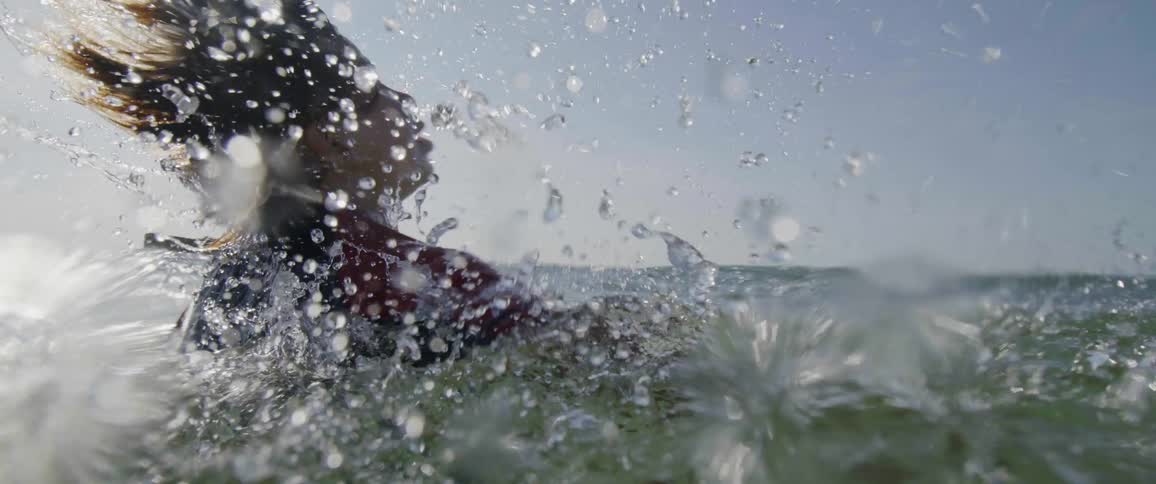 A boy shakes his head after rising to the surface of the ocean