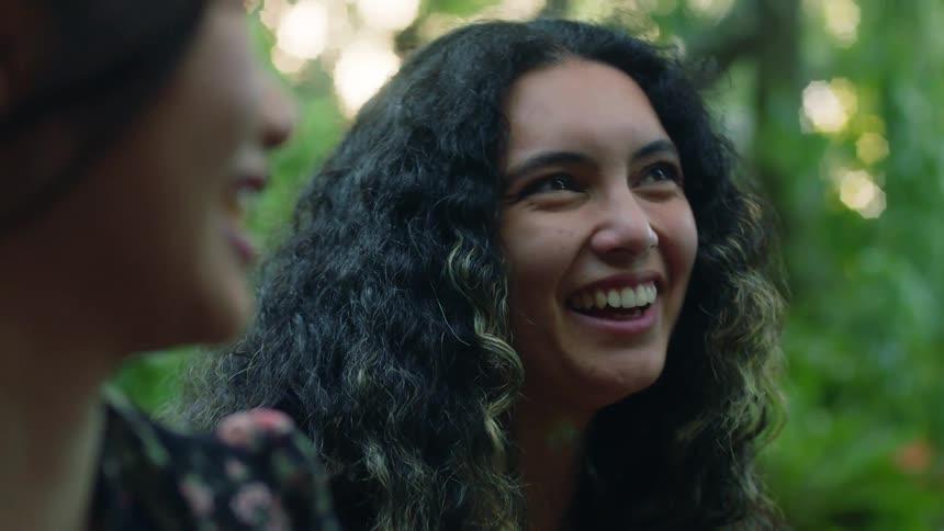 Two women laugh while sitting in the park