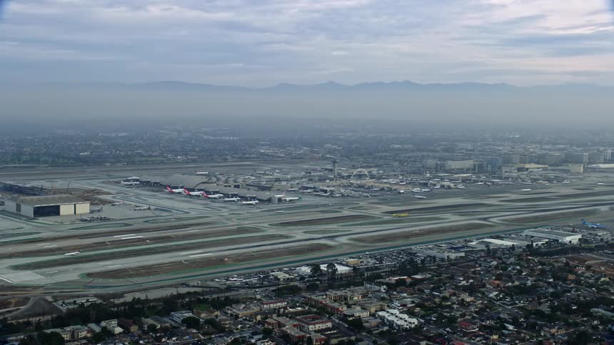 Aerial footage of LAX at sunrise with cloudy skies and light fog