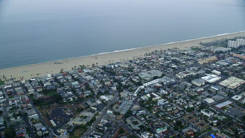 A breathtaking aerial view of Venice California at sunrise featuring homes by the beach and a cloudy shoreline