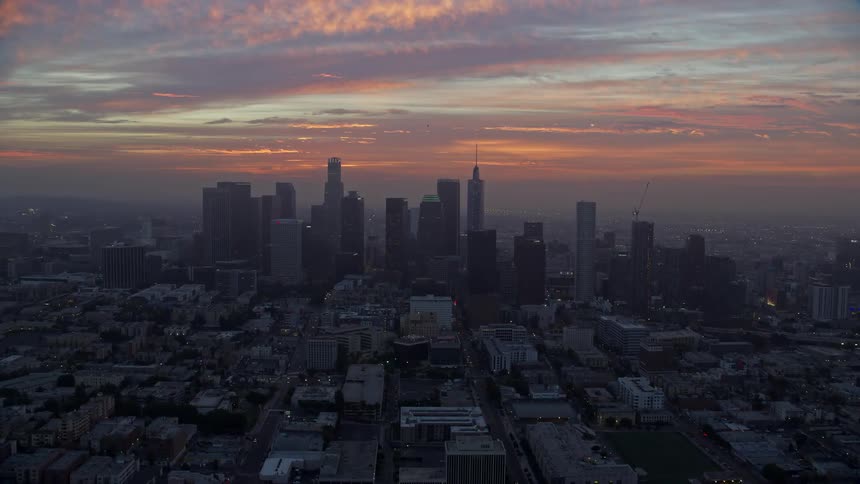An epic aerial view of Downtown Los Angeles skyline during sunrise with cloudy skies and approaching the city