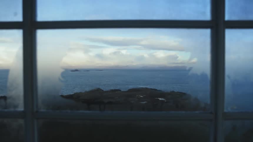 A cliff and ocean reflect off a window