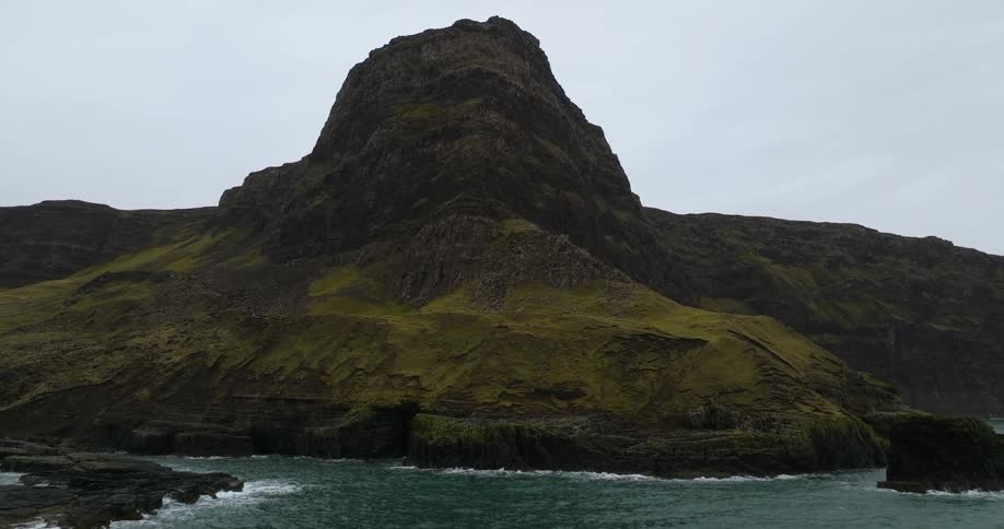Aerial view of the peak of a mountain towering over the coast at daytime