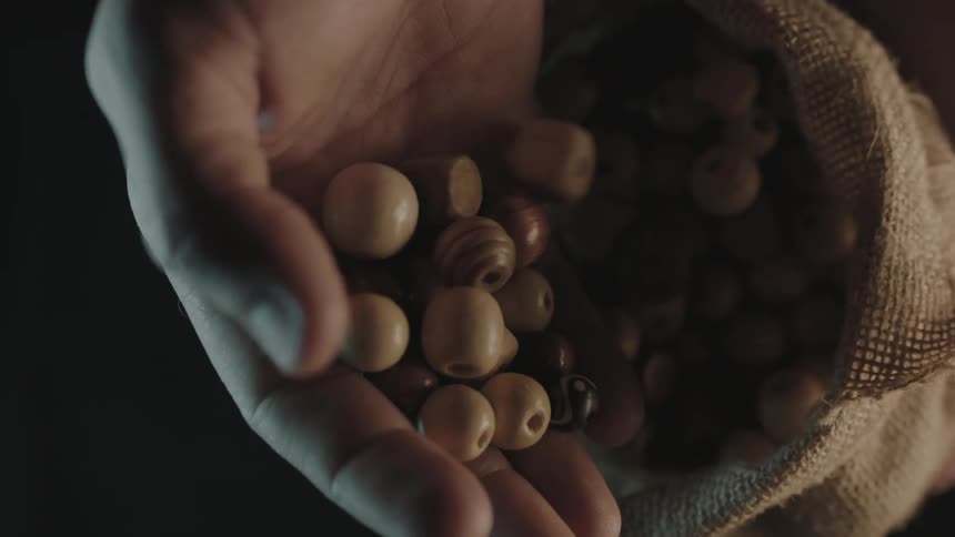 A hand drops objects into a sack